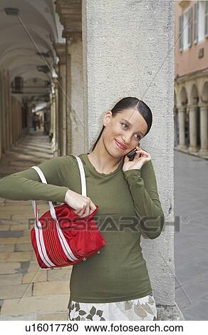 Woman leaning on wall while on cell phone. View Large Photo Image Stock Image - Woman leaning on wall while on cell phone.. Fotosearch