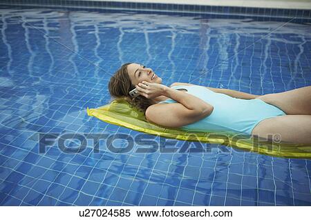 Stock Photography - Woman lying on a lylo on the phone.. Fotosearch