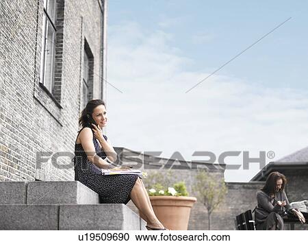 Stock Image - Woman sitting outdoors. Fotosearch