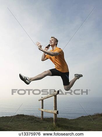 A Man on the phone hurdles fence. View Large Photo Image Stock Photograph - A Man on the phone hurdles fence.. Fotosearch