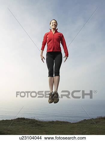 A woman jumping up against a seascape. View Large Photo Image Picture - A woman jumping up against a seascape.. Fotosearch