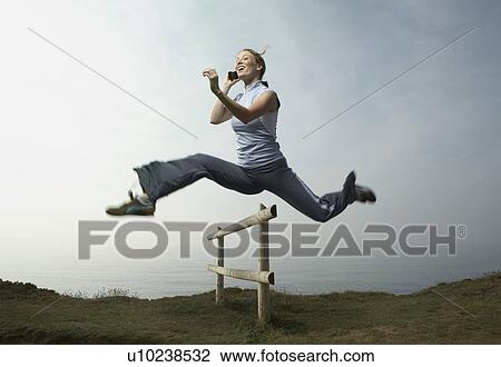 A Woman on the phone hurdles fence. View Large Photo Image Stock Image - A Woman on the phone hurdles fence.. Fotosearch