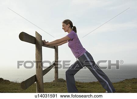 A Woman Stretches on a country fence. View Large Photo Image Stock Image - A Woman Stretches on a country fence.. Fotosearch
