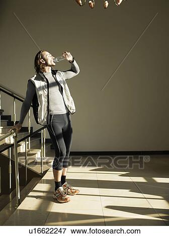 Stock Photo - Mature man drinking water by steps. Fotosearch