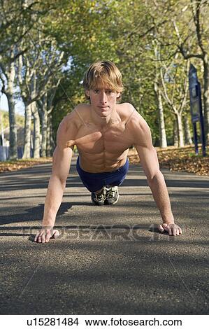 Young man doing push-ups in park. View Large Photo Image Picture - Young man doing push-ups in park.. Fotosearch