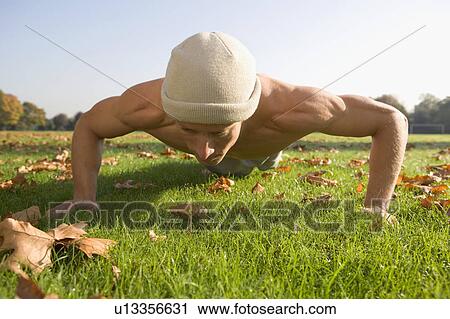 Stock Image - Young man doing push-ups in park.. Fotosearch