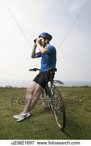 A male cyclist looks through binoculars. View Large Photo Image Stock Photo - A male cyclist looks through binoculars.. Fotosearch