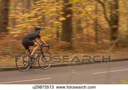 Stock Image - Man cycling in Autumn woods. Fotosearch