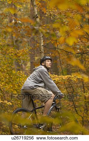 Stock Photograph - Man cycling in Autumn woods. Fotosearch