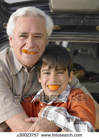Boy (8-10) and grandfather eating oranges, smiling, portrait View Large Photo Image Stock Photo - Boy (8-10) and grandfather eating oranges, smiling, portrait. Fotosearch