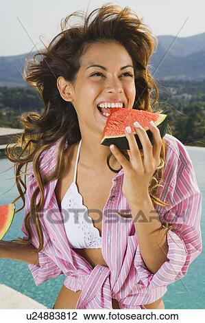 Energetic woman with smile eats watermelon by pool outside. View Large Photo Image Stock Image - Energetic woman with smile eats watermelon by pool outside.. Fotosearch