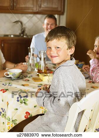 Family sitting at kitchen table eating breakfast smiling. View Large Photo Image Stock Image - Family sitting at kitchen table eating breakfast smiling.. Fotosearch