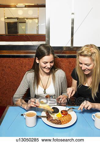 Stock Photography - Two young women sharing a meal in a diner. Fotosearch