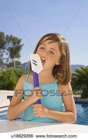 Young girl eating cream with a spatula. View Large Photo Image Stock Photograph - Young girl eating cream with a spatula.. Fotosearch
