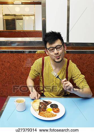 Young man eating fried meal in diner alone View Large Photo Image Picture - Young man eating fried meal in diner alone. Fotosearch