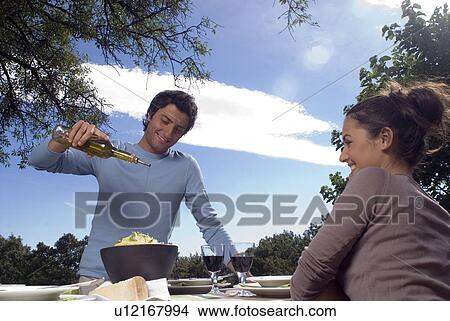 Picture - Young man putting olive oil on pasta. Fotosearch