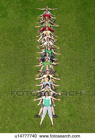 Stock Image - Group lying back on each other in a line on grass. Fotosearch