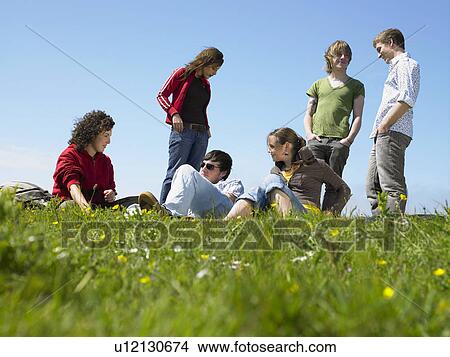 Group of young people relaxing in the grass. View Large Photo Image Picture - Group of young people relaxing in the grass.. Fotosearch