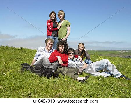 Group of young people relaxing in the grass. View Large Photo Image Stock Photo - Group of young people relaxing in the grass.. Fotosearch