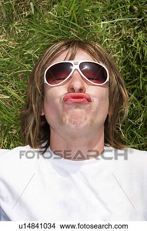 Male lying on grass wearing sunglasses pouting View Large Photo Image Picture - Male lying on grass wearing sunglasses pouting. Fotosearch