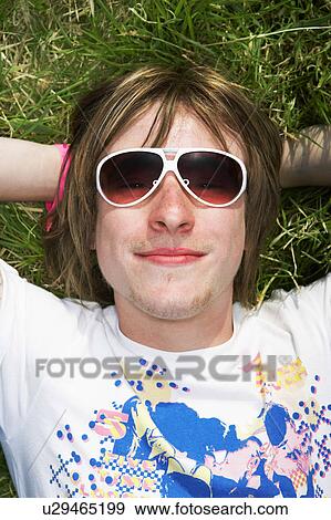 Male lying on grass wearing sunglasses View Large Photo Image Stock Photo - Male lying on grass wearing sunglasses. Fotosearch