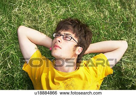 Male lying on grass with arms behind head View Large Photo Image Stock Photograph - Male lying on grass with arms behind head. Fotosearch