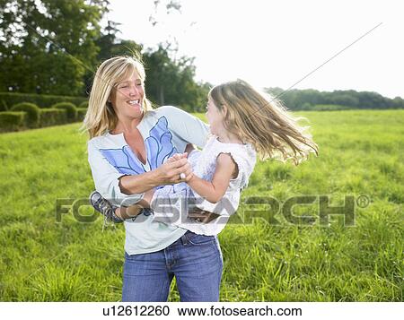 Stock Image - Mother and daughter playing in a field.. Fotosearch