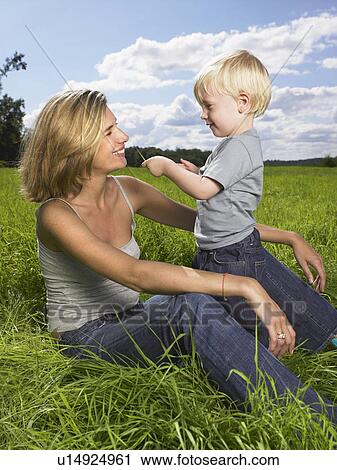 Stock Image - Mother and son playing in a field.. Fotosearch