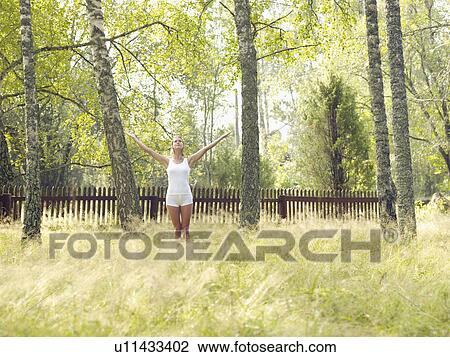 Woman standing by a wooden fence with arms outstretched. View Large Photo Image Stock Image - Woman standing by a wooden fence with arms outstretched.. Fotosearch