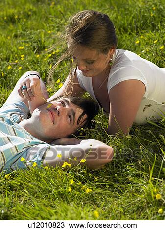 Stock Image - You couple lying in the grass.. Fotosearch