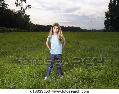 Young girl standing in a field. View Large Photo Image Stock Image - Young girl standing in a field.. Fotosearch
