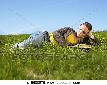 Young woman lying in the grass. View Large Photo Image Stock Photograph - Young woman lying in the grass.. Fotosearch