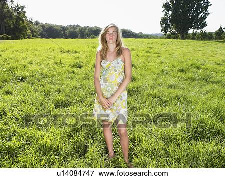 Young woman standing in a field. View Large Photo Image Stock Photo - Young woman standing in a field.. Fotosearch