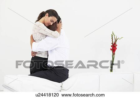 Embracing couple sitting on back of sofa View Large Photo Image Stock Image - Embracing couple sitting on back of sofa. Fotosearch