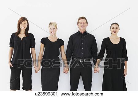 Stock Image - Four business people holding hands. Fotosearch