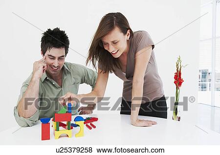 Stock Photo - Man and woman happily build model house. Fotosearch