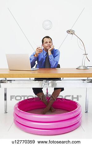 Man in office with feet in paddling pool View Large Photo Image Stock Photo - Man in office with feet in paddling pool. Fotosearch
