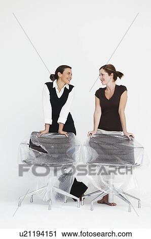 Stock Image - Two women smiling in new office. Fotosearch