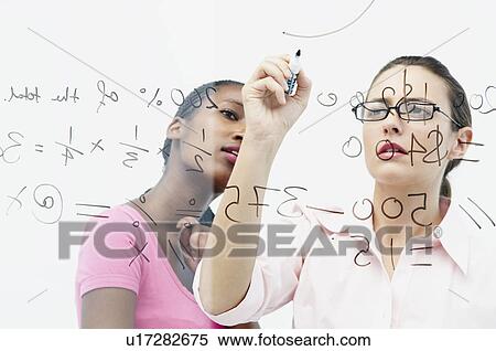 Stock Photography - Two women write on glass panel. Fotosearch