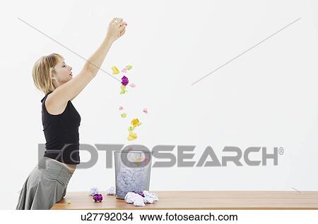 Picture - Woman drops paper into bin. Fotosearch