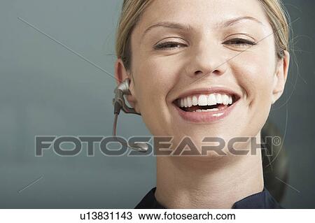 Stock Image - Close-Up portrait of Business woman with telephone headset / earpiece.. Fotosearch
