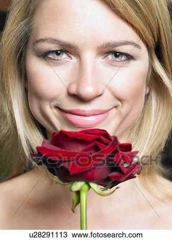 Young woman holding red rose, smiling, portrait View Large Photo Image Stock Image - Young woman holding red rose, smiling, portrait. Fotosearch