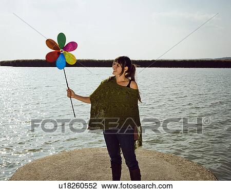 Girl holding toy windmill by lake. View Large Photo Image Stock Image - Girl holding toy windmill by lake.. Fotosearch