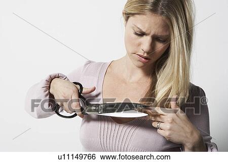 Young woman cutting her own hair with a large pair of scissors. View Large Photo Image Stock Photograph - Young woman cutting her own hair with a large pair of scissors.. Fotosearch