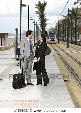 Businessman and businesswoman talking on pavement by tram tracks View Large Photo Image Stock Image - Businessman and businesswoman talking on pavement by tram tracks. Fotosearch