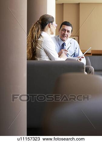 Businessman and woman sitting in armchairs using laptop View Large Photo Image Stock Image - Businessman and woman sitting in armchairs using laptop. Fotosearch