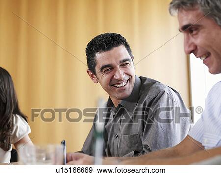 Stock Photo - Businessman in meeting with colleagues, smiling. Fotosearch