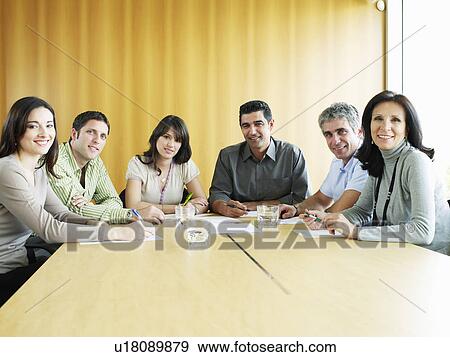 Stock Photo - Colleagues sitting in meeting room, smiling, portrait. Fotosearch