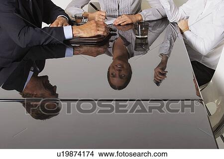 Three business people's reflection in a table. View Large Photo Image Picture - Three business people's reflection in a table.. Fotosearch