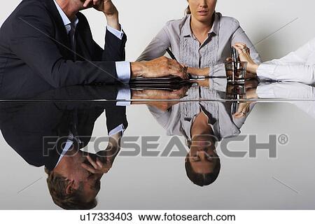 Stock Image - Three business people's reflection in a table.. Fotosearch